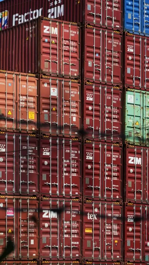 pexels-photo-13600203-13600203 Vertical shot of colorful, stacked shipping containers at a bustling cargo port.
