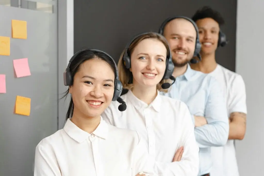 pexels-photo-7682342-7682342 Smiling customer service team wearing headsets in an office setting, ready to assist clients.